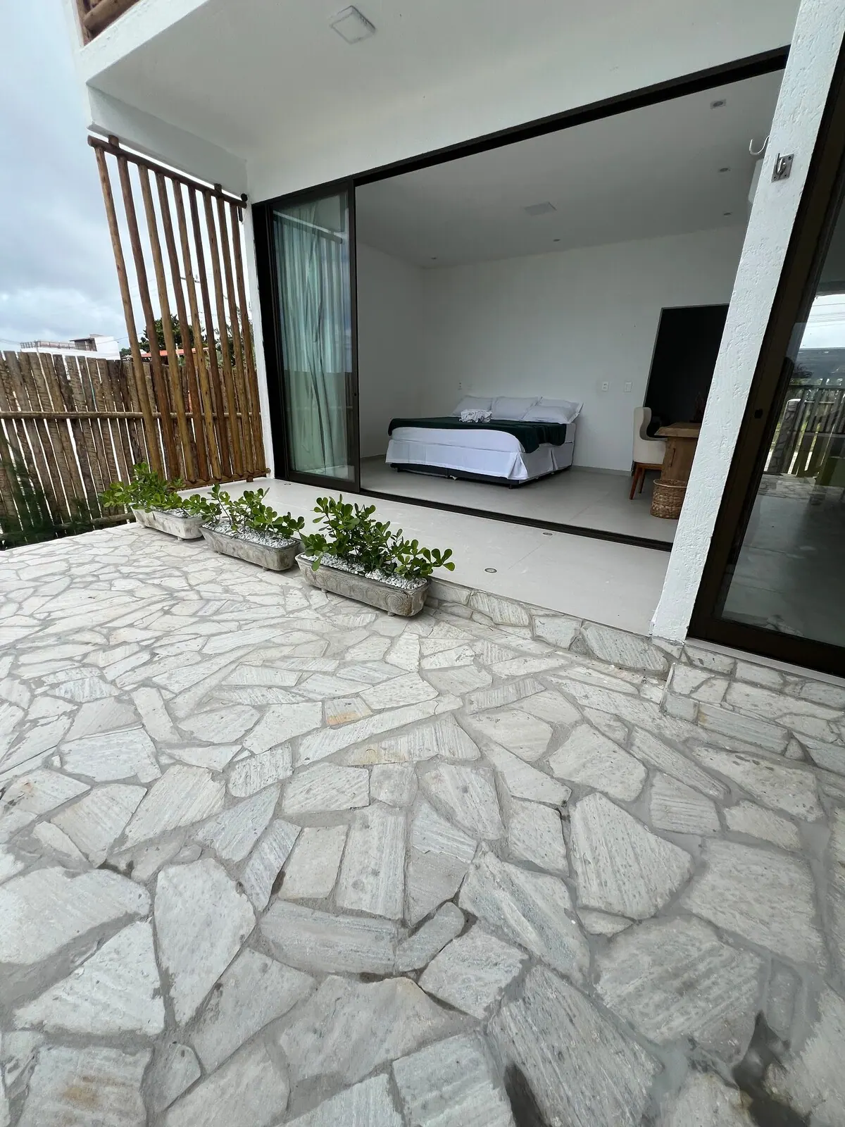 Quarto do térreo aberto para o pátio de pedra pela porta de correr
