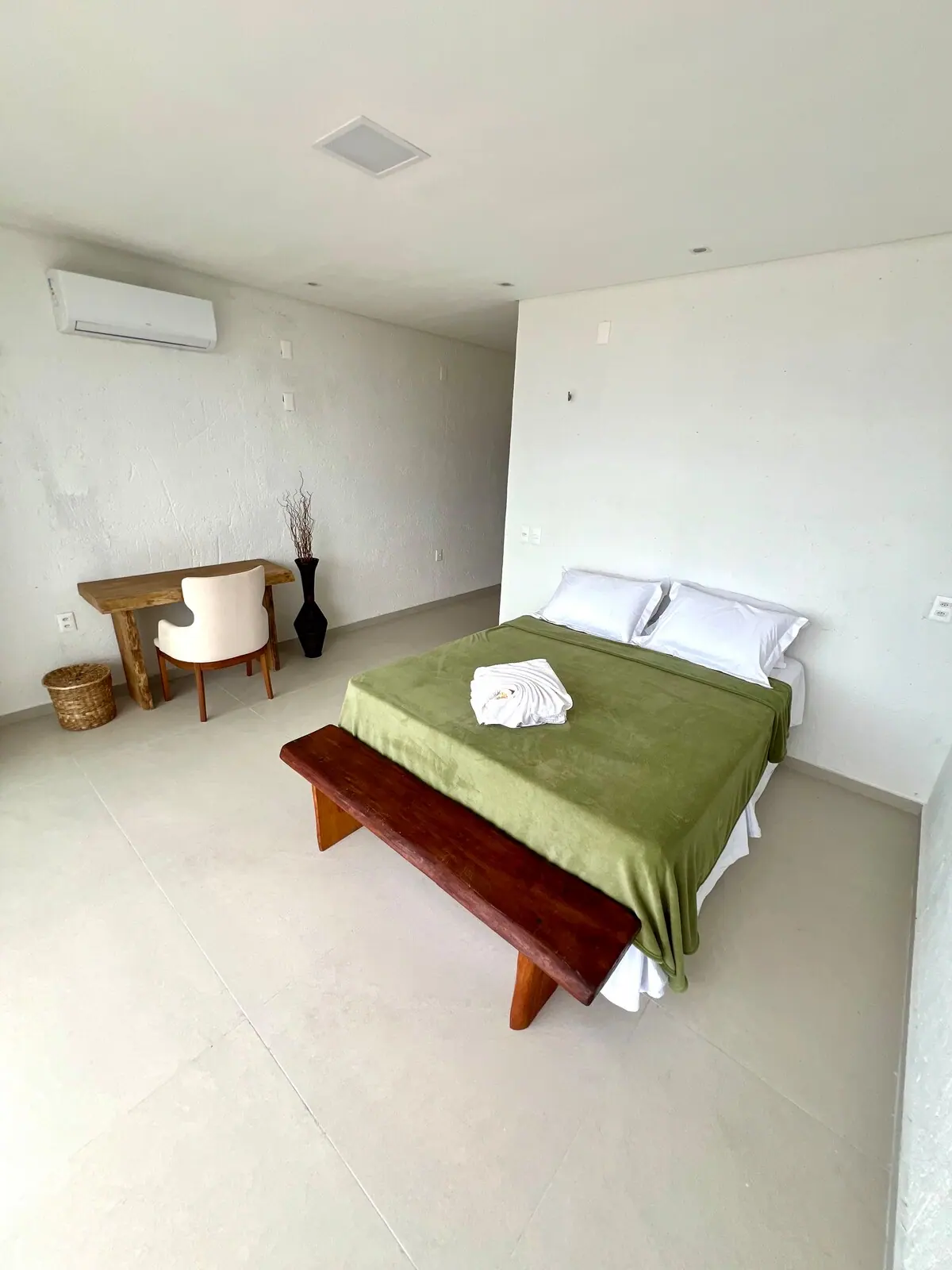 Quarto amplo no térreo, com cama, banco de madeira e ar-condicionado