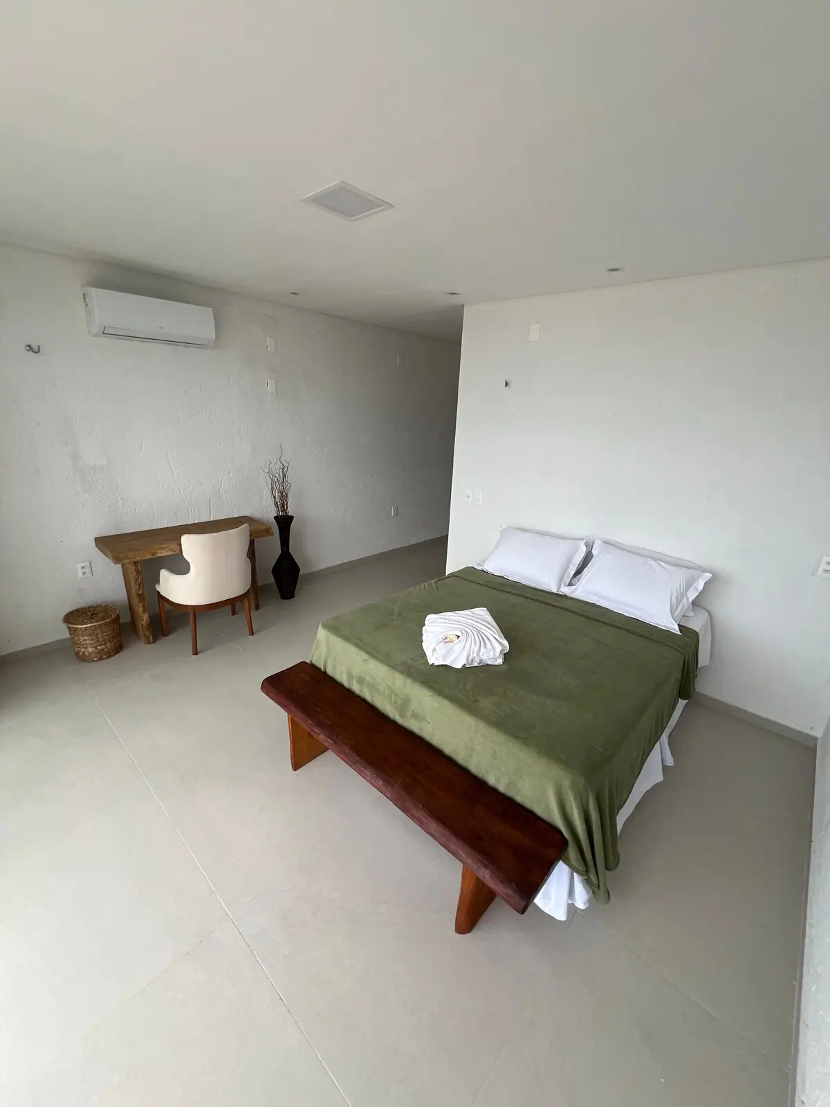 Quarto amplo com cama, banco de madeira e escrivaninha