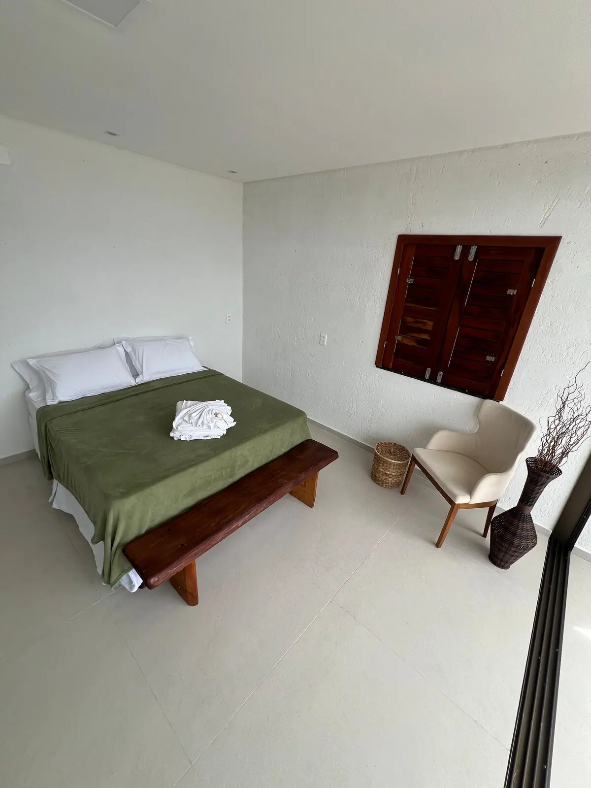 Quarto com cama, banco de madeira e janela de madeira