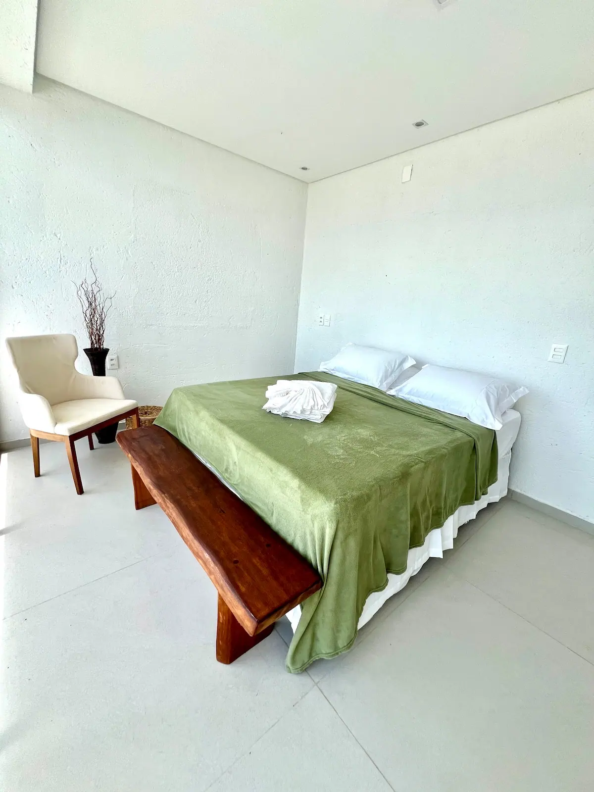 Suíte 1, no térreo, com cama king, banco de madeira e poltrona