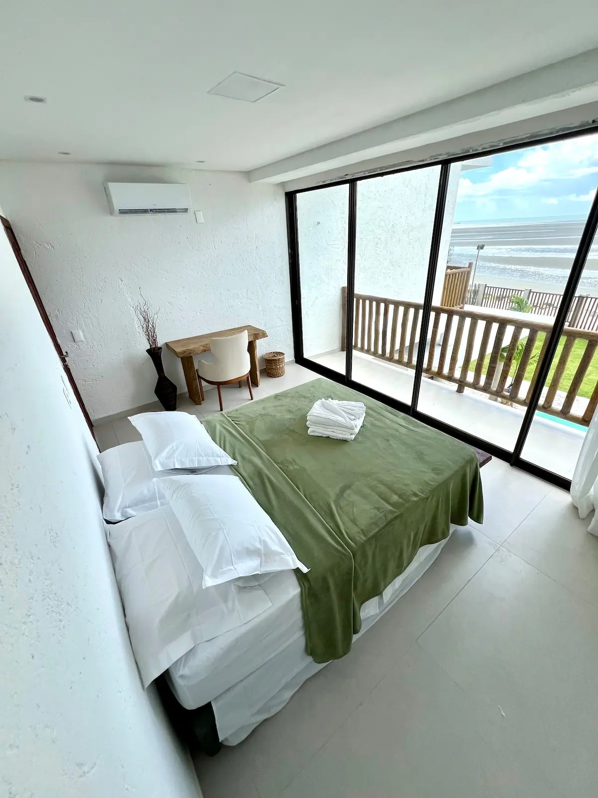 Suíte 2, no primeiro andar, com cama e janela de vidro para a praia