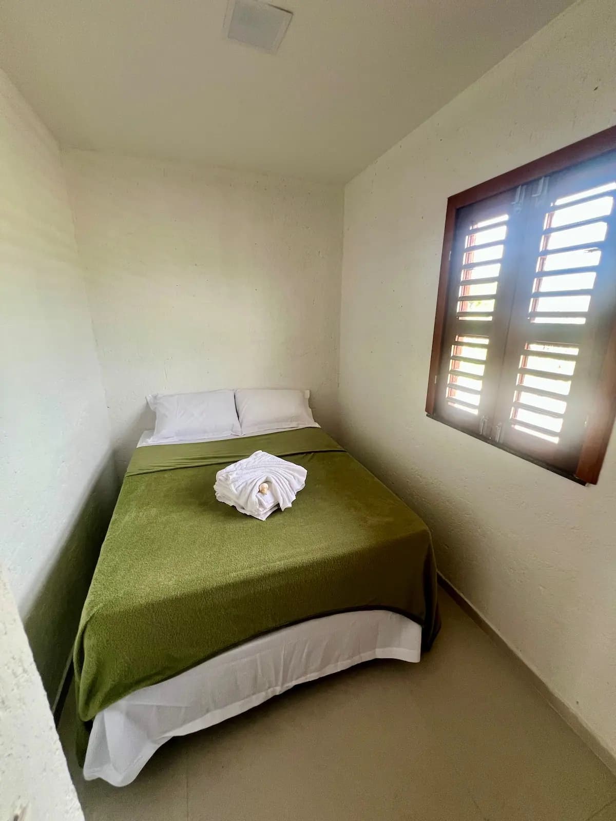Quarto independente com cama de casal e janela de madeira