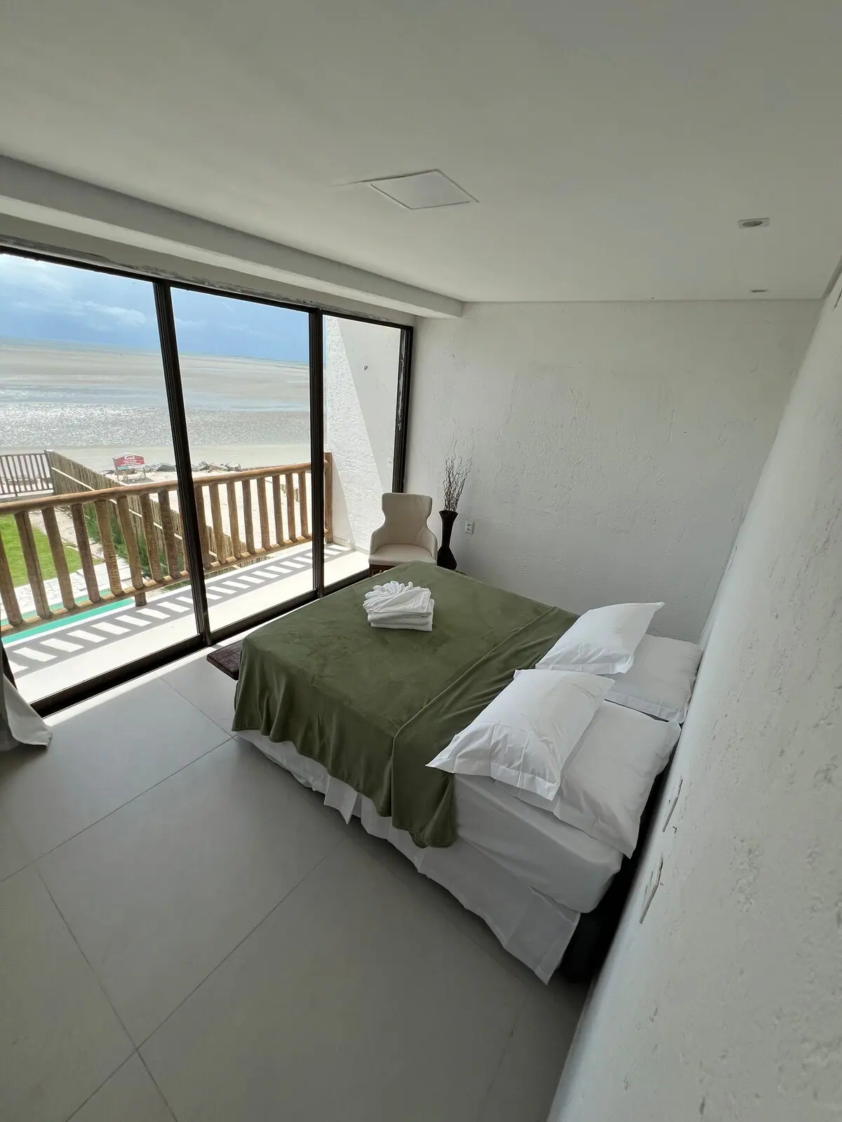 Quarto com cama e janela inteira para a praia