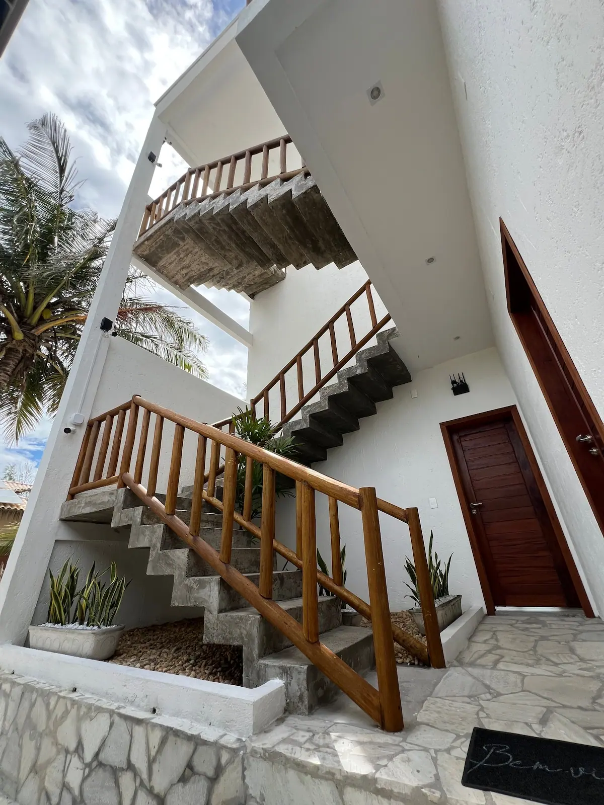 Escada externa de madeira e pedra que sobe pela lateral da casa
