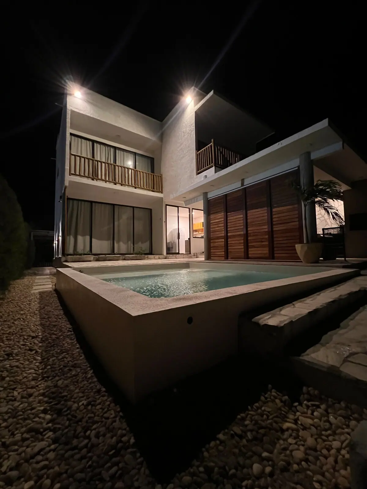 Casa Ventus à noite, iluminada, com a piscina em primeiro plano