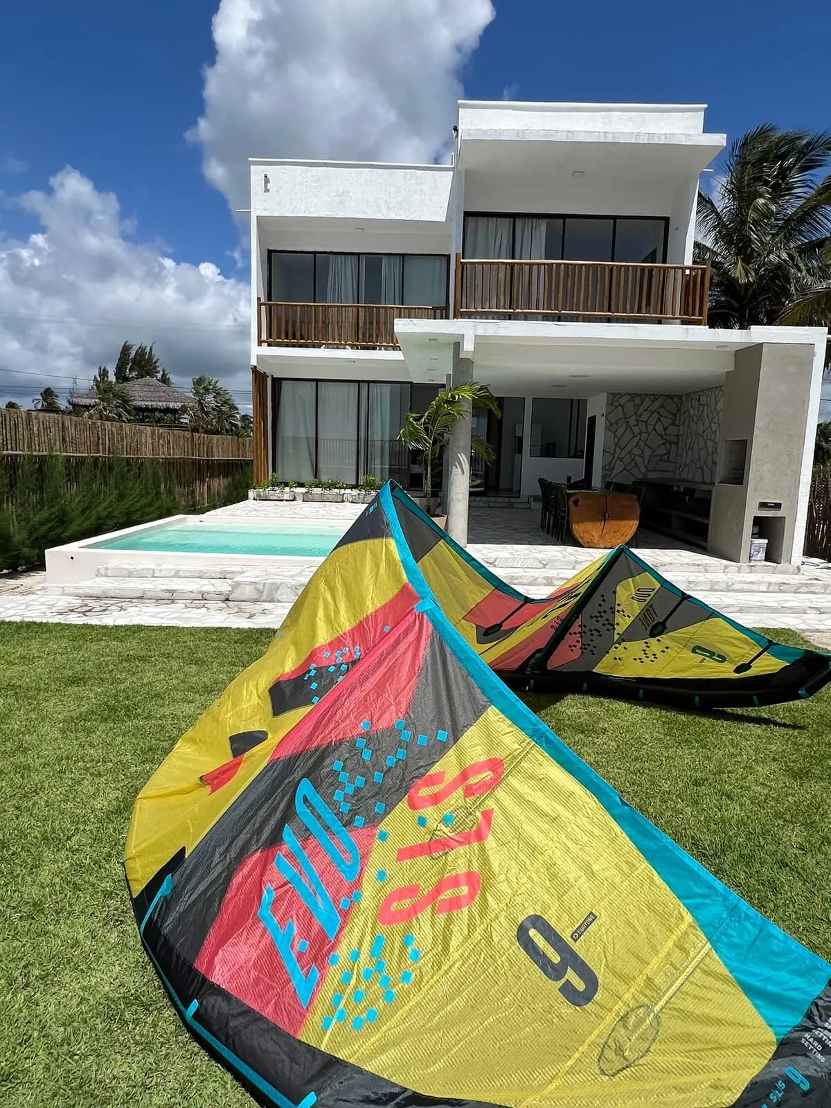 Kites abertos no gramado, com a fachada da casa ao fundo