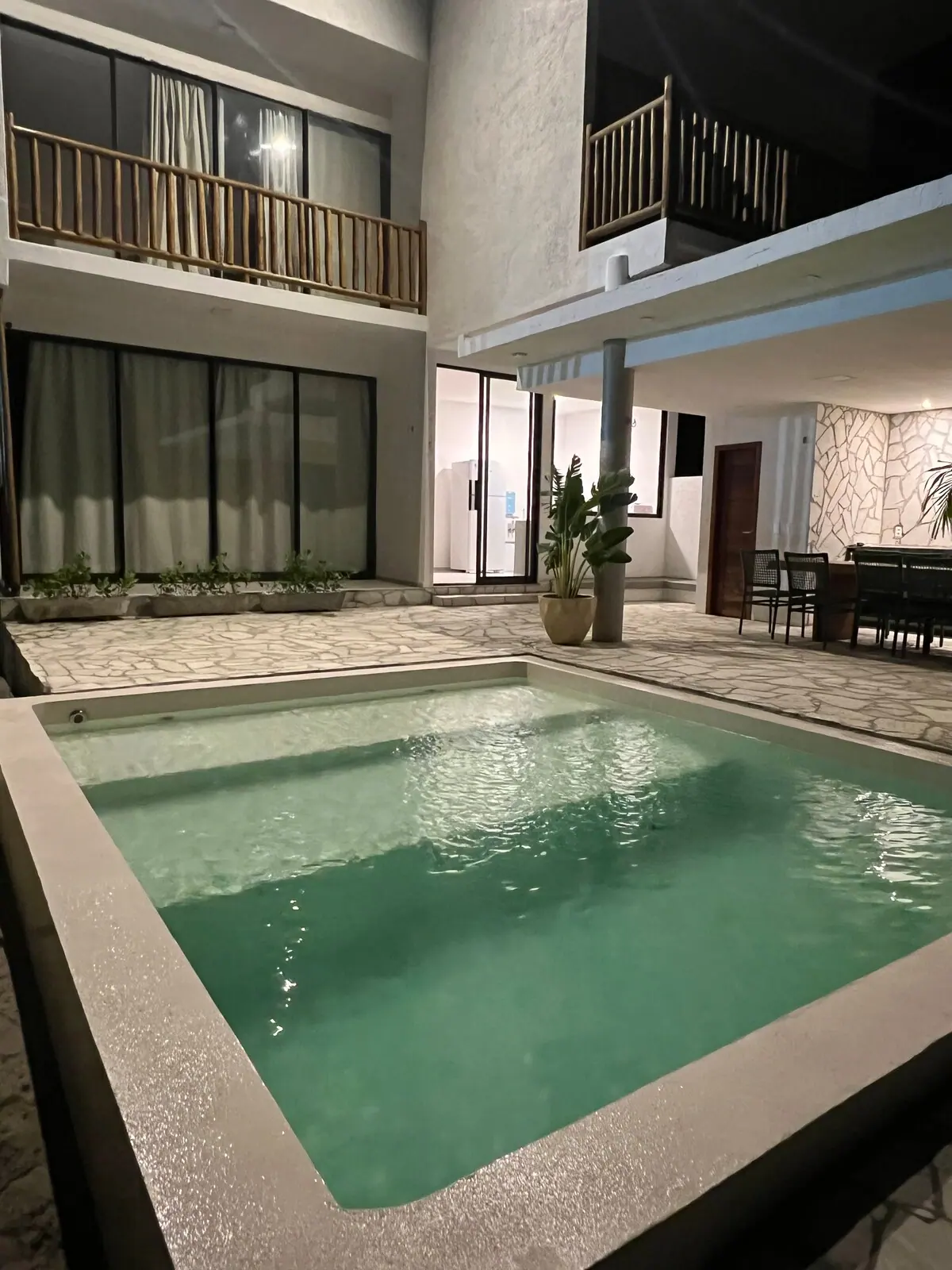 Piscina em primeiro plano e a fachada de dois andares ao fundo