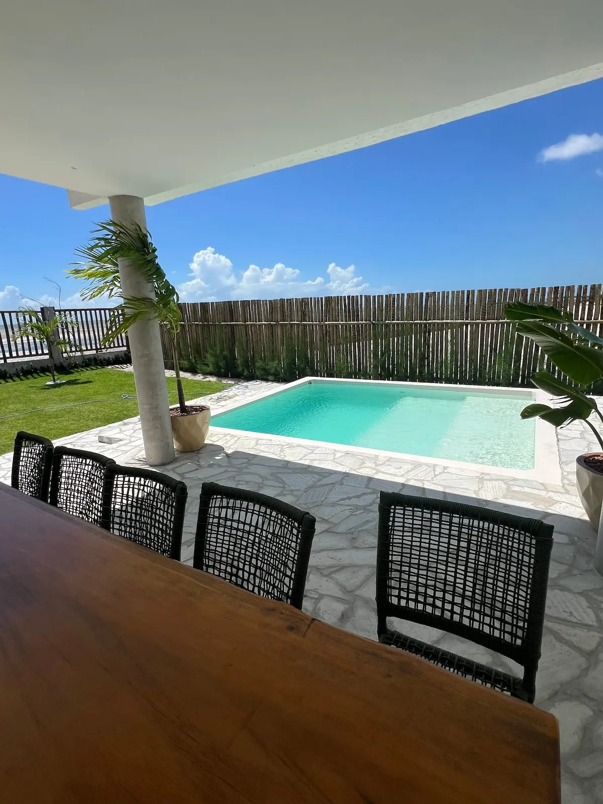 Cadeiras e mesa de madeira na borda da piscina