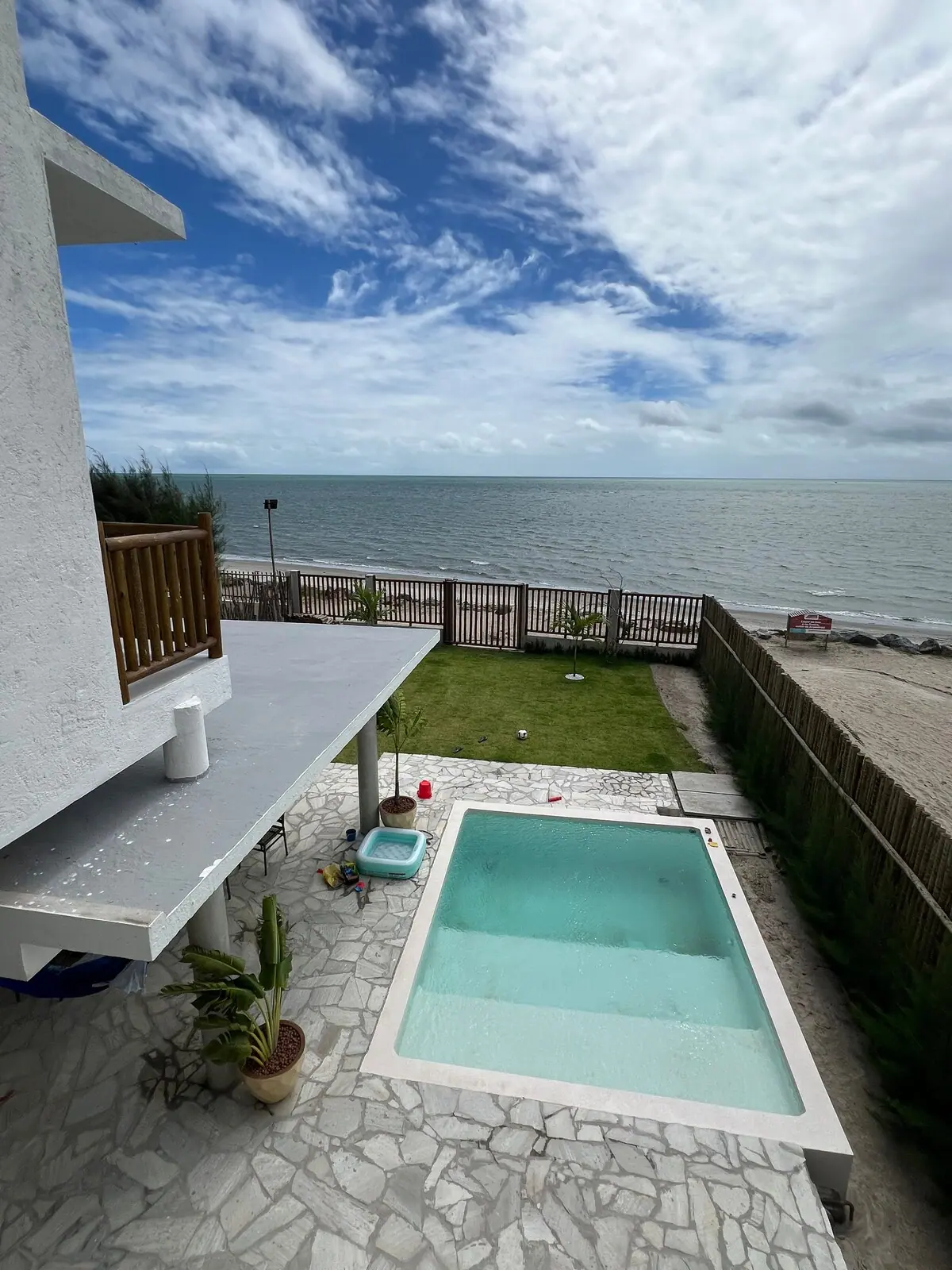 Piscina vista de cima, com a praia e o mar logo depois do gramado